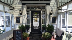 A spa entrance with a 'NOW OPEN' sign, a welcome sign, and a list of services like organic skincare and massage. - Stevenson Inn & Spa (Essa)