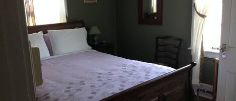 Ein Schlafzimmer mit einem hölzernen Bett, einem Nachttisch, einem Stuhl und einer Tür.