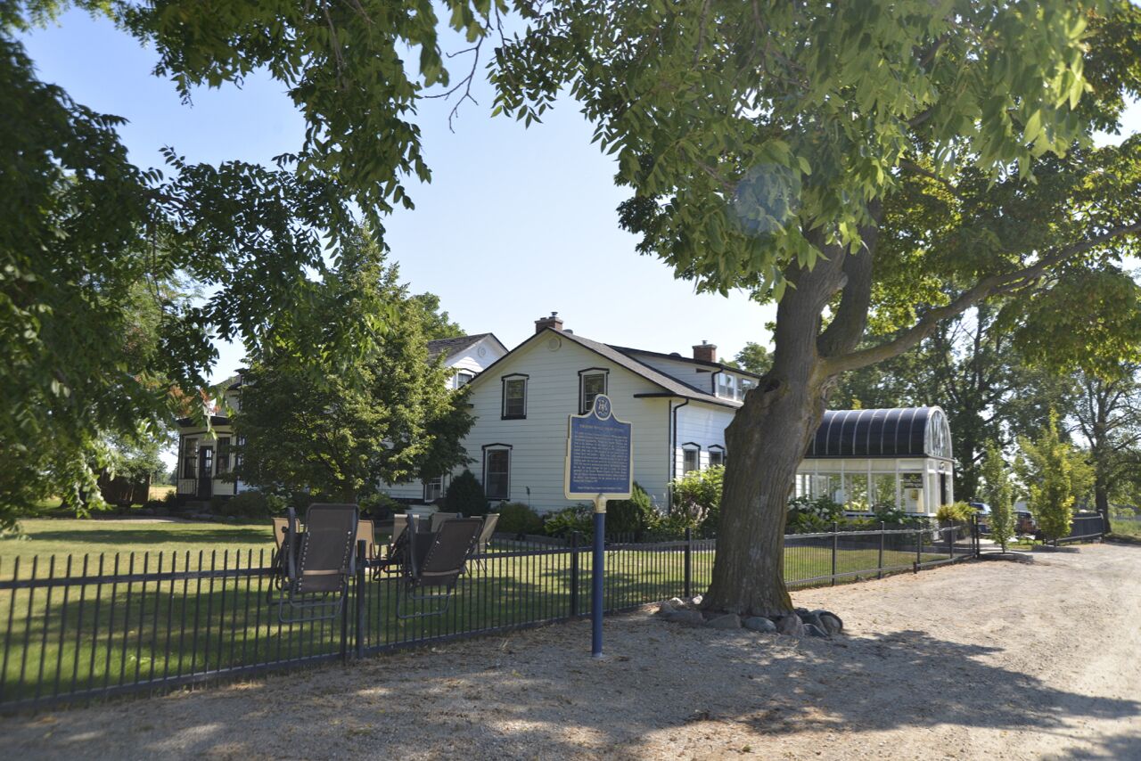 Ein historisches Haus mit einem eingezäunten Garten und einem großen Baum.