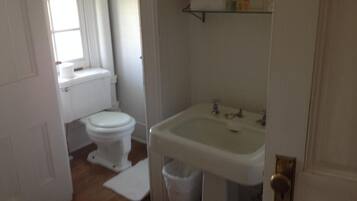 Un baño pequeño y limpio con inodoro, lavamanos y una ventana pequeña.