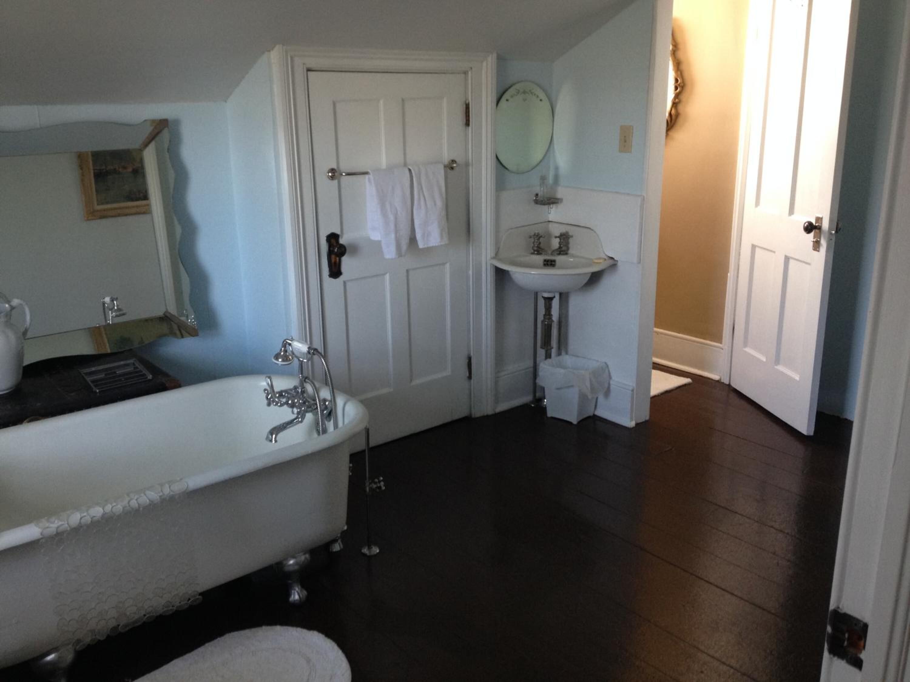 A bathroom with a freestanding bathtub, a sink, and a mirror.