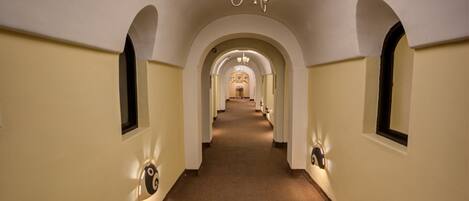 A long, narrow hallway with arched ceilings and a carpeted floor.