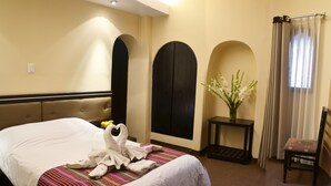 Una habitación de hotel con una cama grande, una mesita con un florero y una silla.
