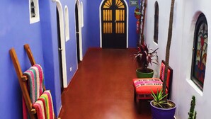 Un pasillo estrecho con suelo de baldosas, un banco de madera, una silla y una planta en maceta.