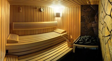 A sauna with wooden benches and a stone wall.