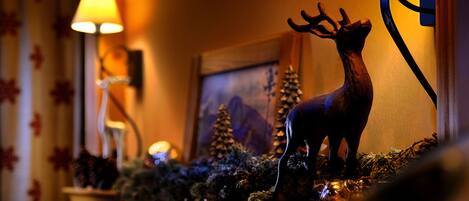 A warmly lit room with a decorative deer figurine on a shelf, a lamp, and a framed picture on the wall.