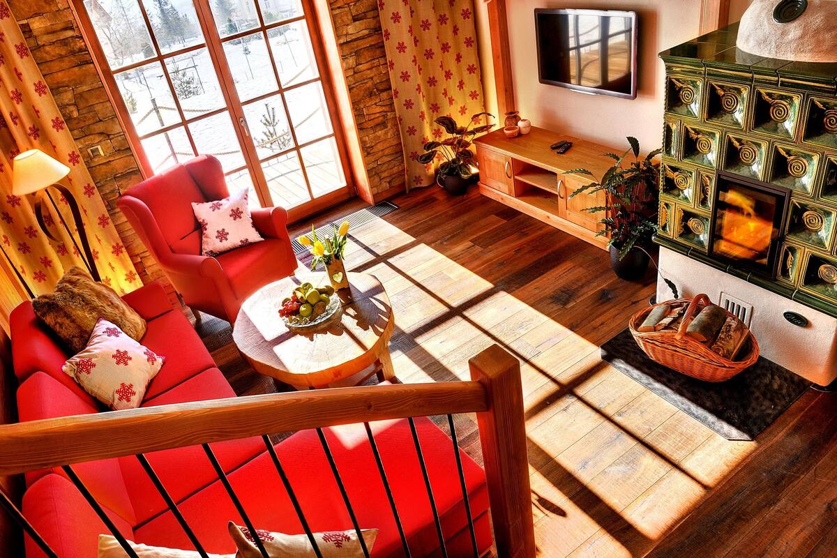 Een gezellige woonkamer met een rode bank, een houten salontafel en een open haard.