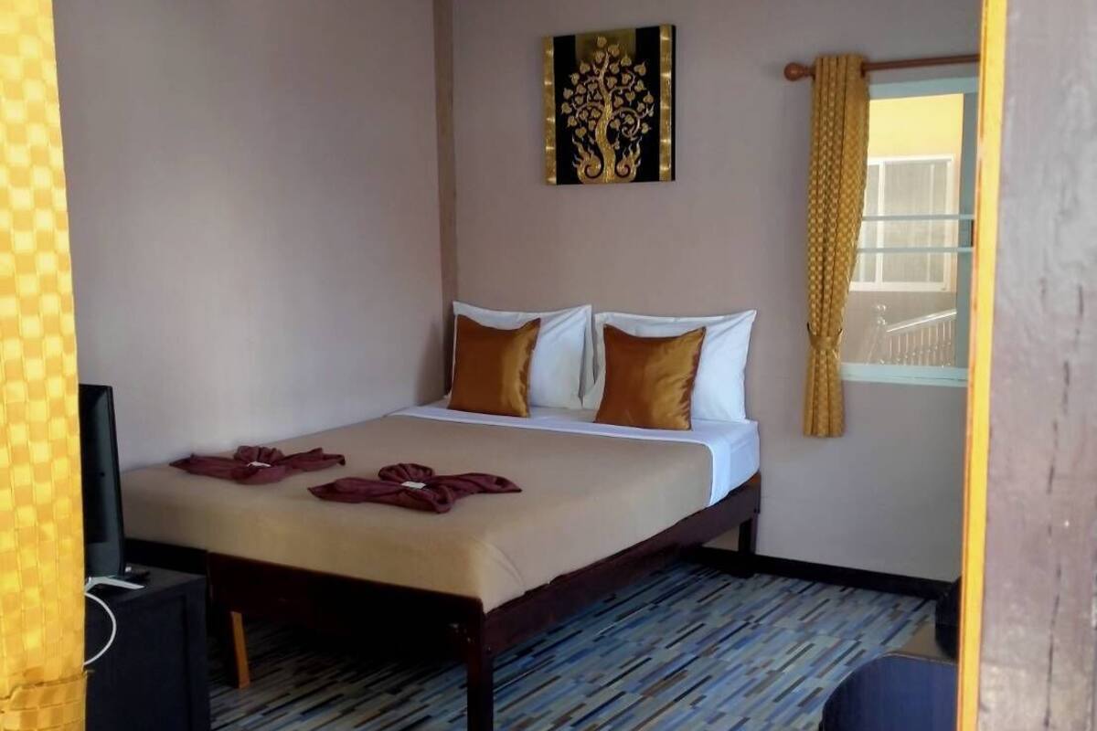 A hotel room with a bed, a television, and a window with curtains.