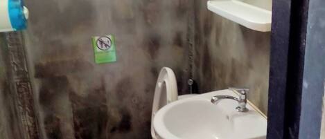 Un baño pequeño con inodoro, lavamanos y espejo.