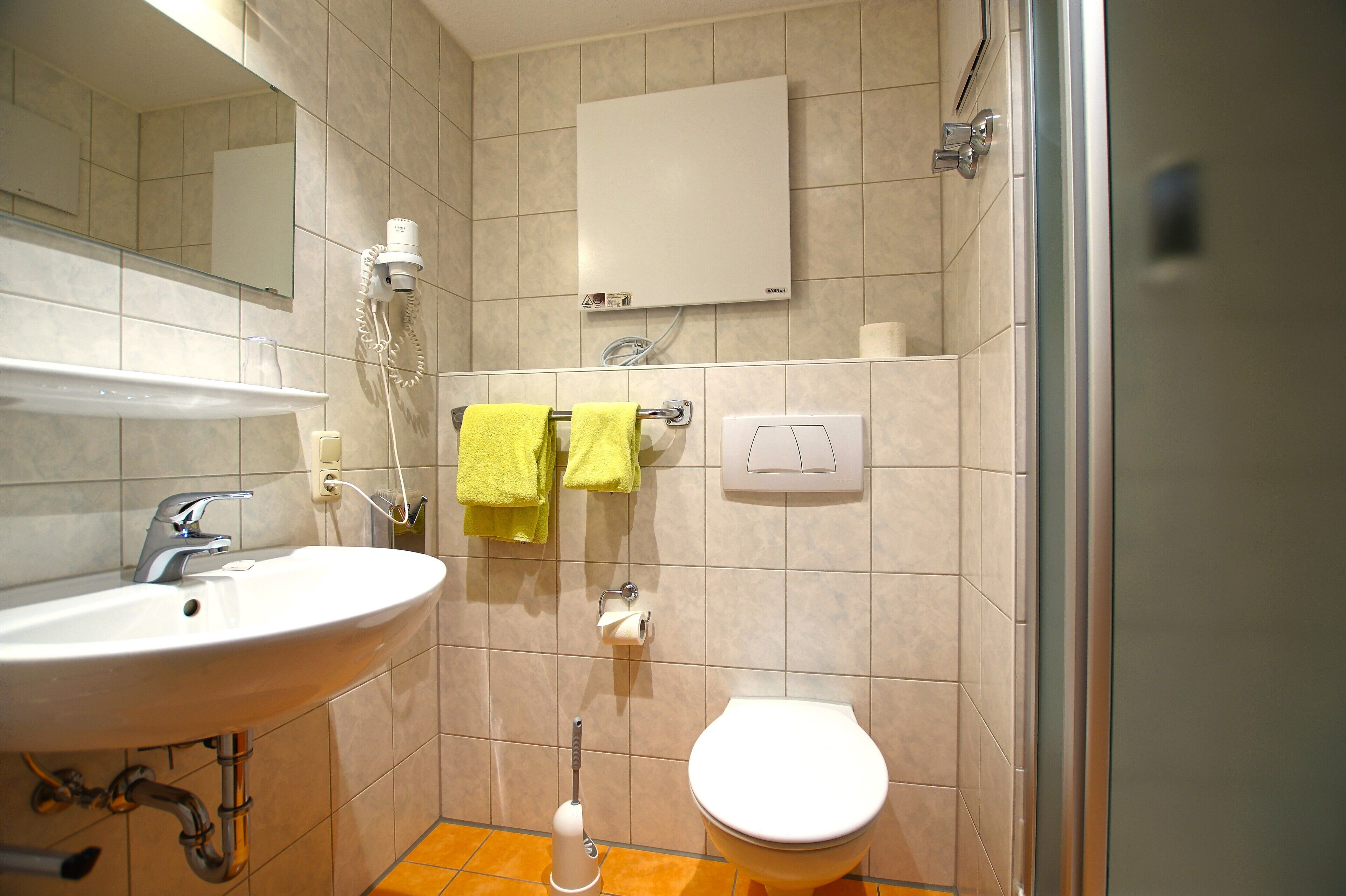 Un bagno con lavandino, specchio, porta asciugamani, toilette e zona doccia.
