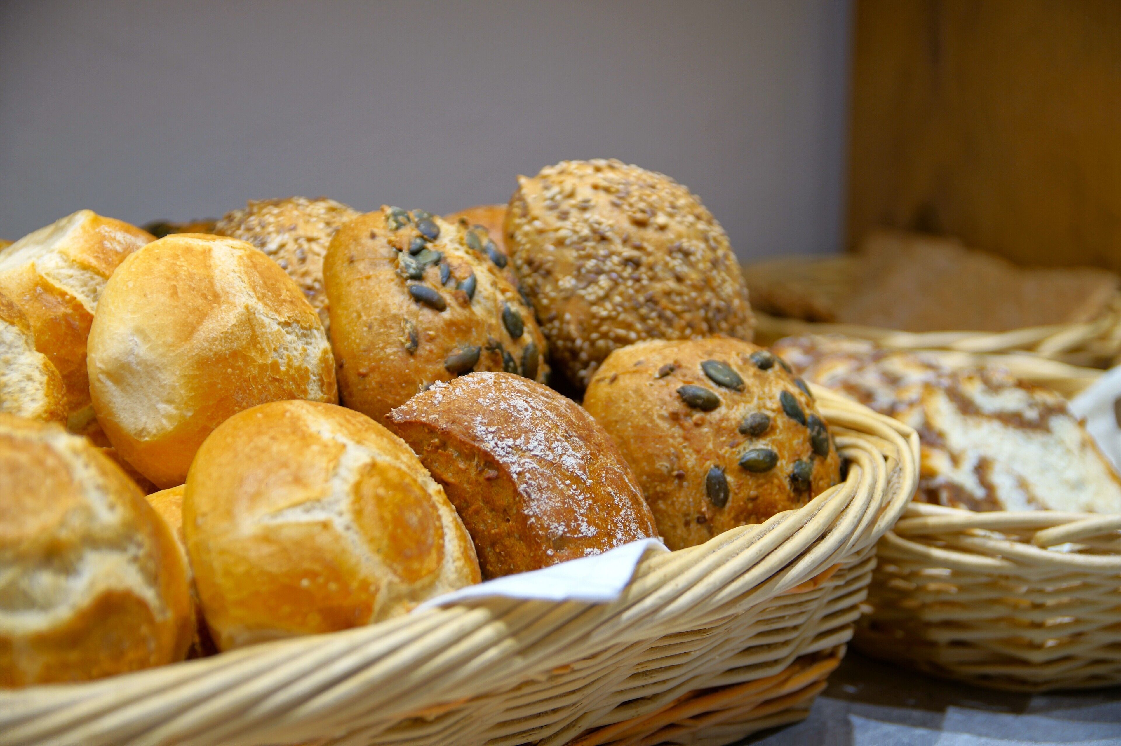 A basket of various breads, including rolls and seeded buns.