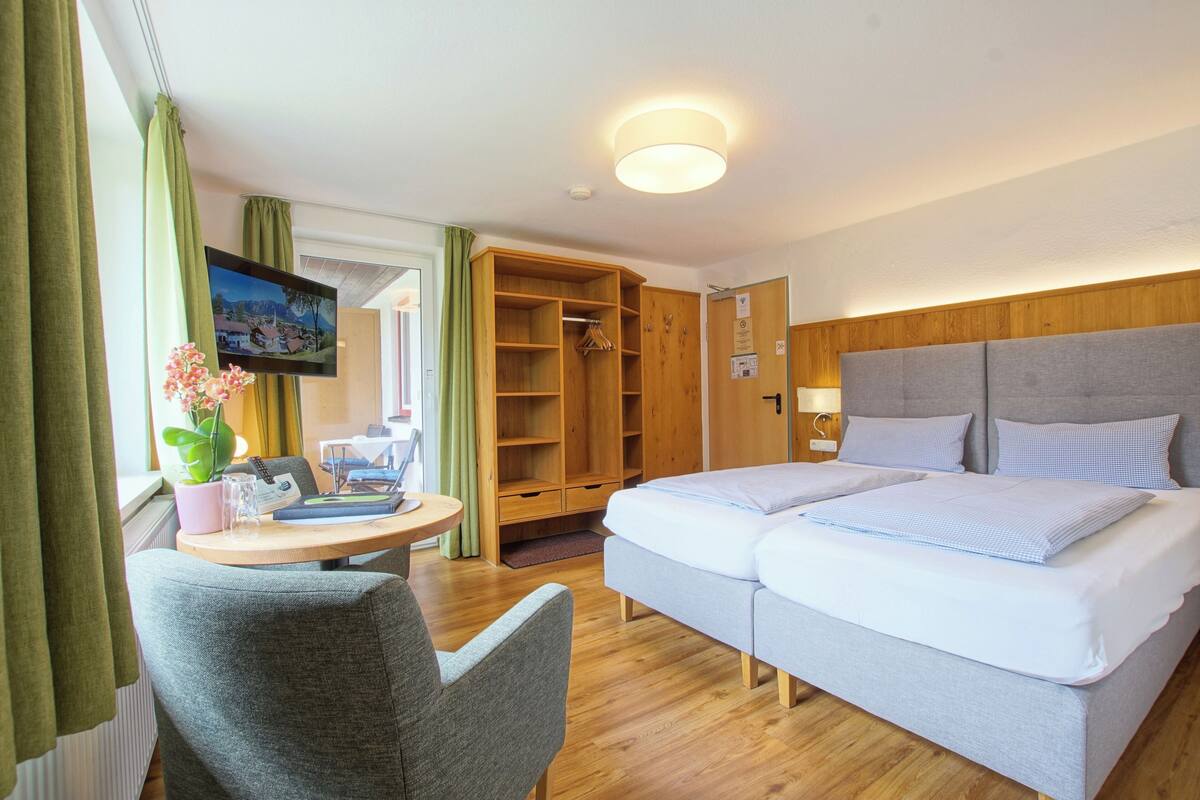 Hotellihuone, jossa on parivuode, työpöytä tuolilla, televisio ja vaatekaappi.