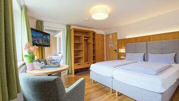 A hotel room with a double bed, a desk with a chair, a TV, and a wardrobe.