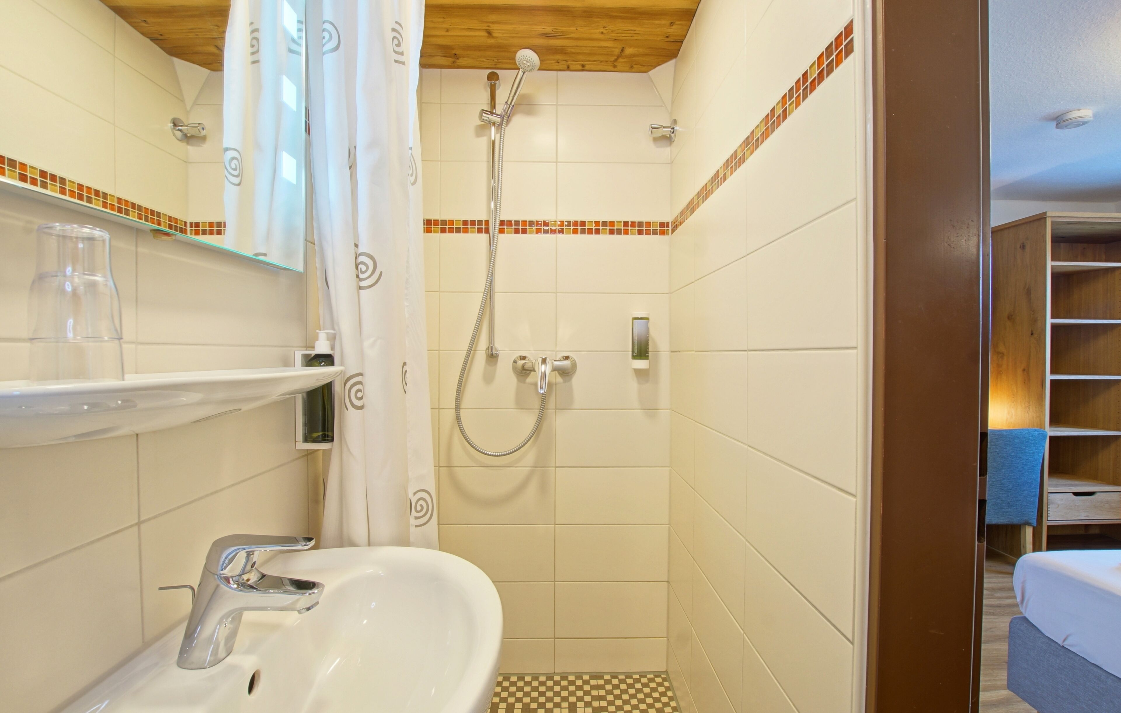 Un baño con ducha, lavamanos y espejo.