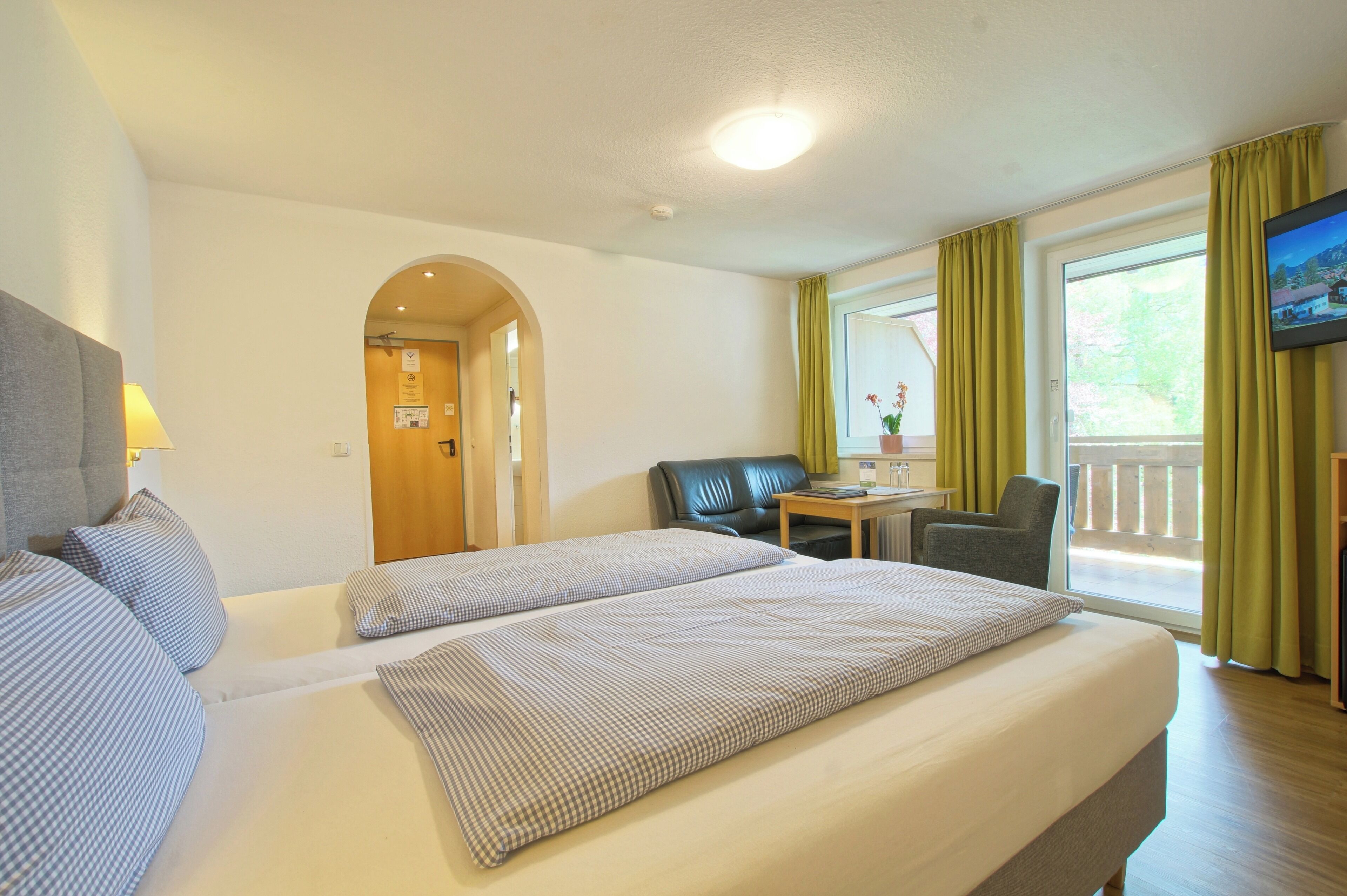 A hotel room with a large bed, a desk, a chair, and a television.