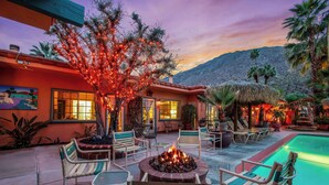 A poolside area with a fire pit, lounge chairs, and a building with a mountain backdrop. - Coyote Inn - 21 and Over - A Town & Desert Boutique Hotel (Palm Springs)