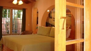 A bedroom with a wooden bed, a window with curtains, and a view of the outside. - Coyote Inn - 21 and Over - A Town & Desert Boutique Hotel (Palm Springs)
