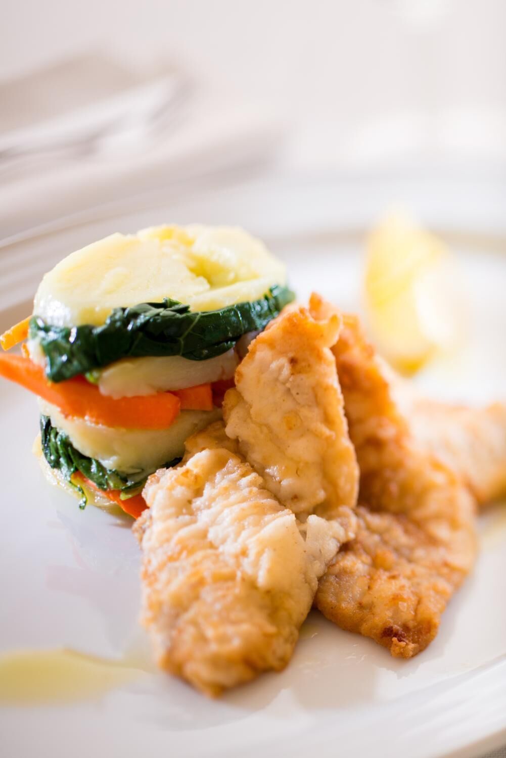Ein Teller mit Fischfilet, Kartoffelpüree und gemischtem Gemüse.