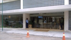 A building entrance with a glass facade, two orange traffic cones, and a person standing near the entrance. - VIP Inn Beira (Beira)