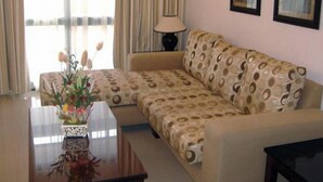 A living room with a sofa, a coffee table with a floral vase, and a lamp. - VIP Inn Beira (Beira)