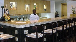 A bar area with a bartender, bar counter, and multiple bar stools. - VIP Inn Beira (Beira)