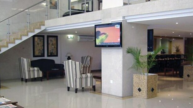 A spacious lobby with a staircase, a flat-screen TV mounted on a pillar, and a dining area with tables and chairs. - VIP Inn Beira (Beira)