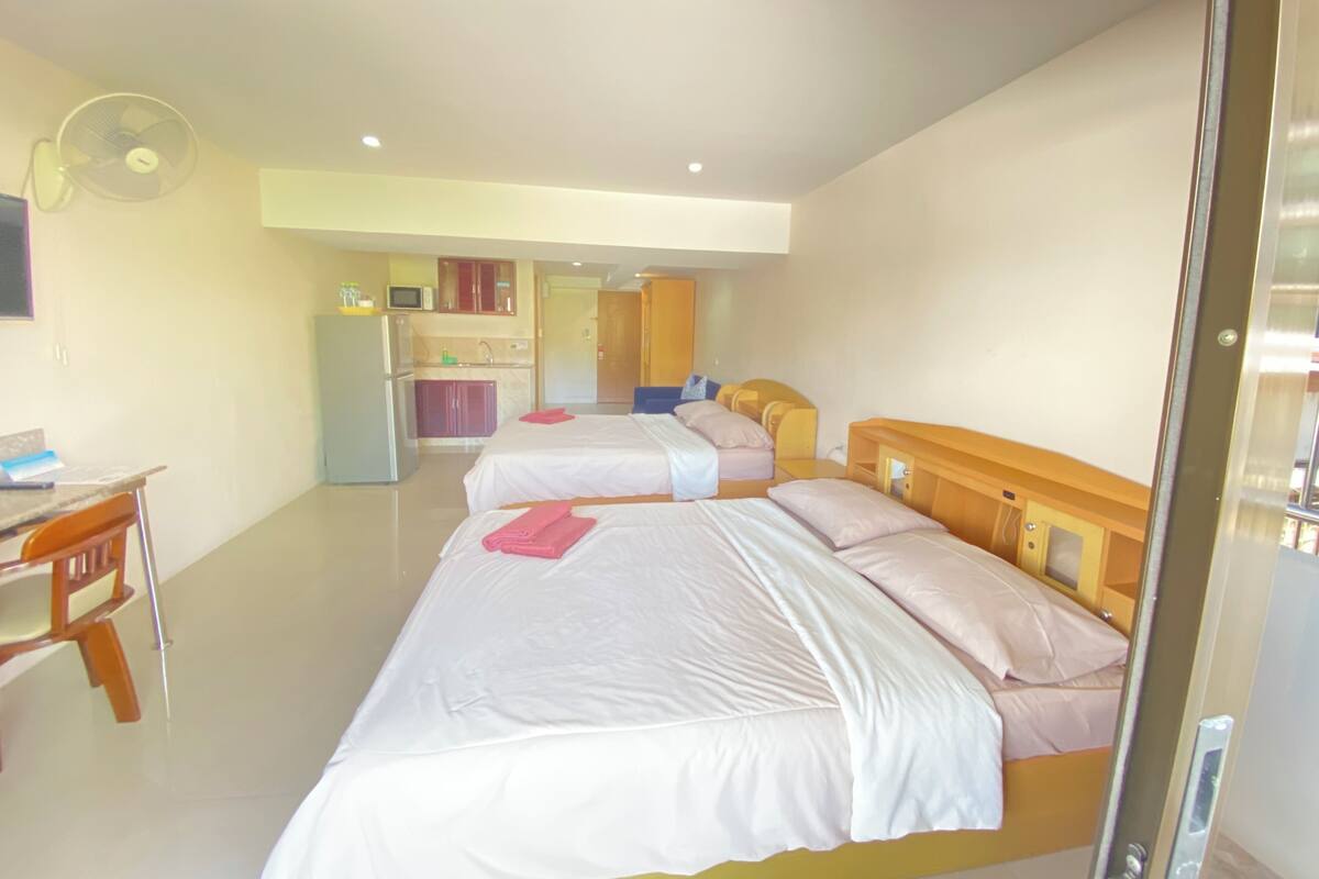 Habitación de hotel con dos camas, un escritorio, un refrigerador, un microondas y un ventilador.
