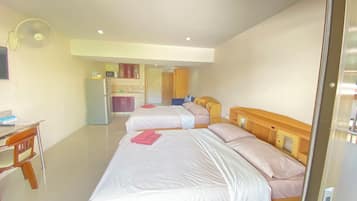 Habitación de hotel con dos camas, un escritorio, un refrigerador, un microondas y un ventilador.