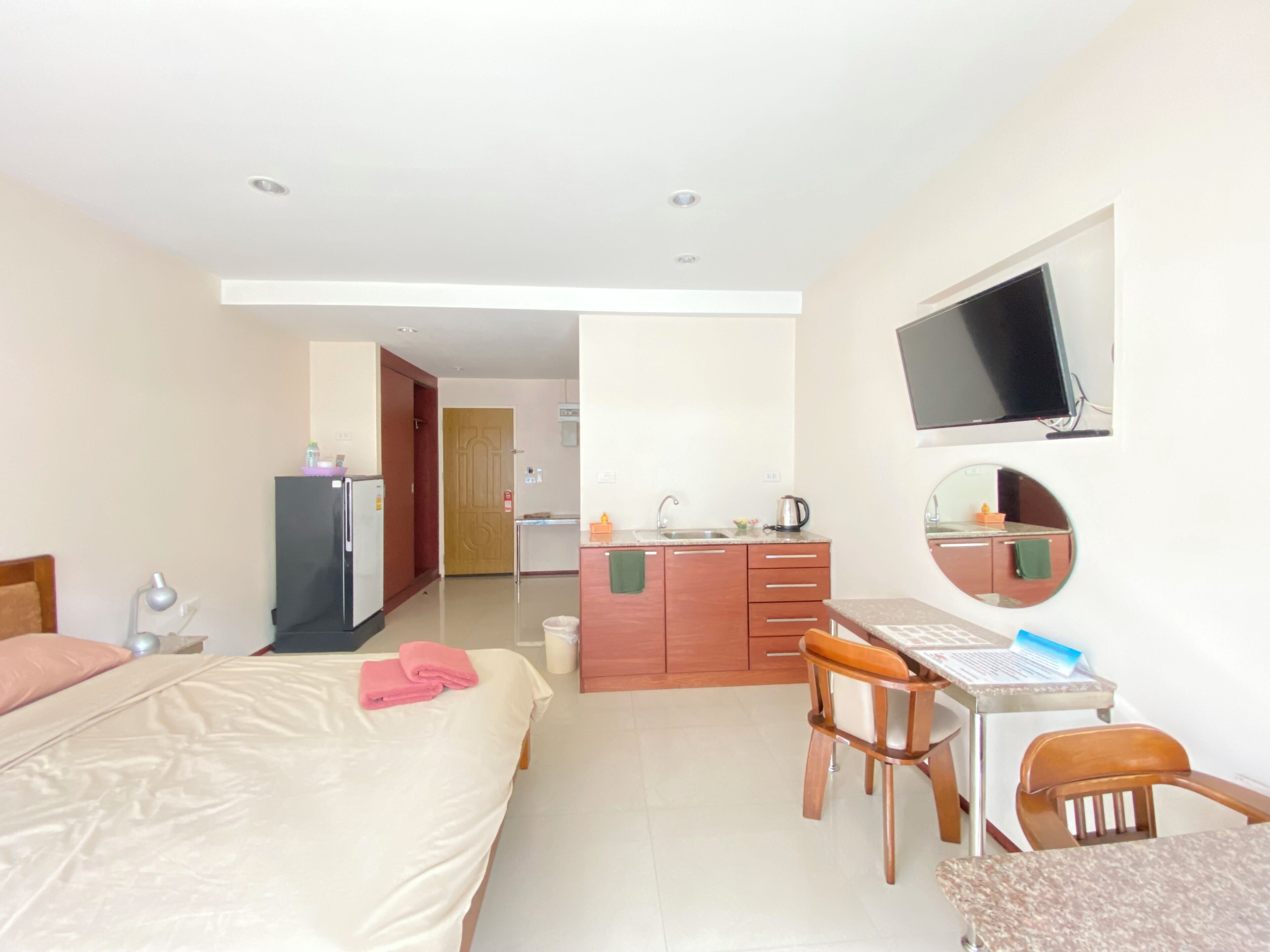 Una habitación de hotel con cama, escritorio, sillas, televisor y kitchenette.