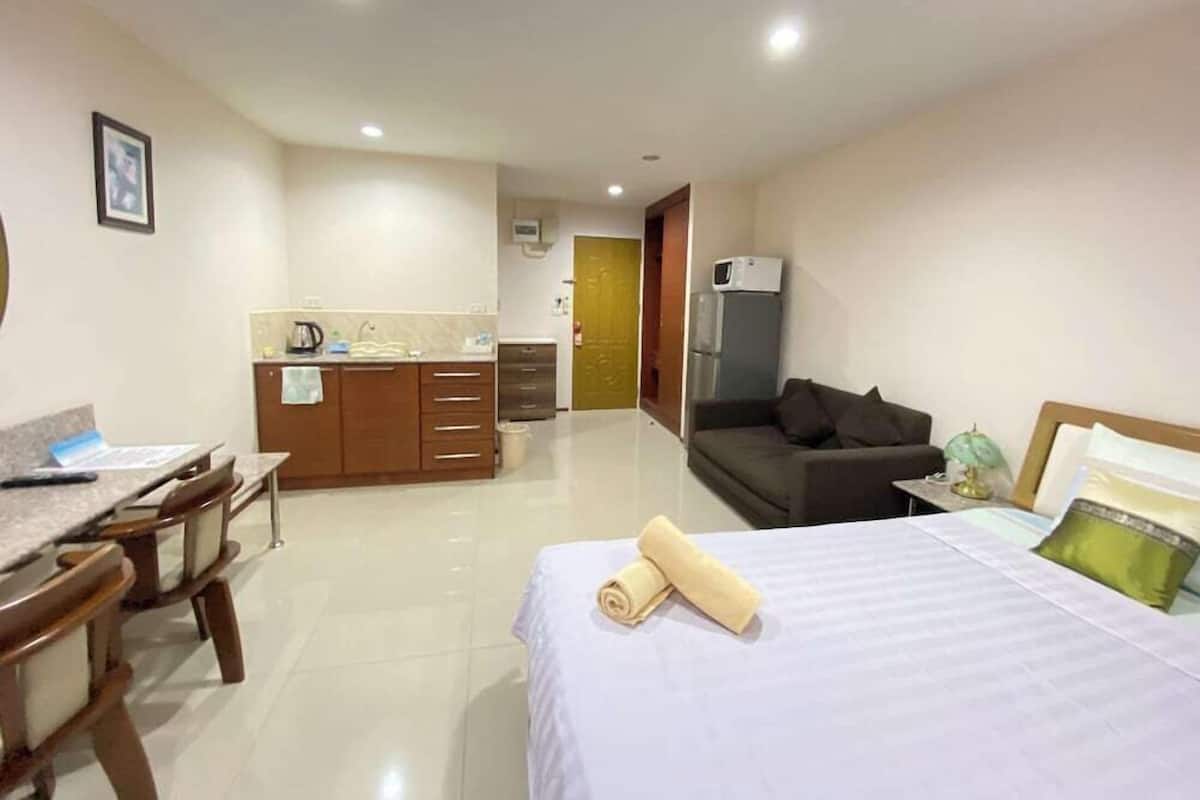 Una habitación de hotel con cama, escritorio, kitchenette y sofá.