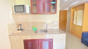 Una cocina compacta con microondas integrado, un lavamanos y un armario.