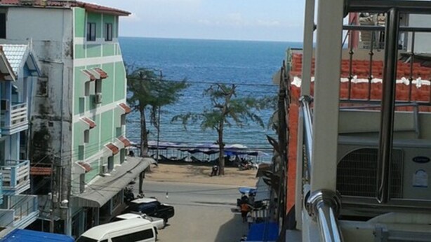 Vista de la calle con edificios, coches aparcados y vista al mar.