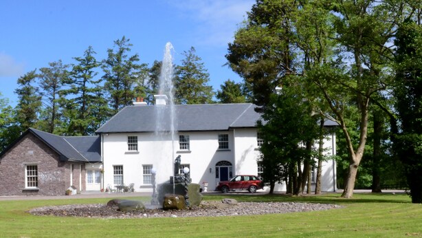 A white building with a fountain in front, surrounded by trees. - Cannaway House B&B (Macroom)