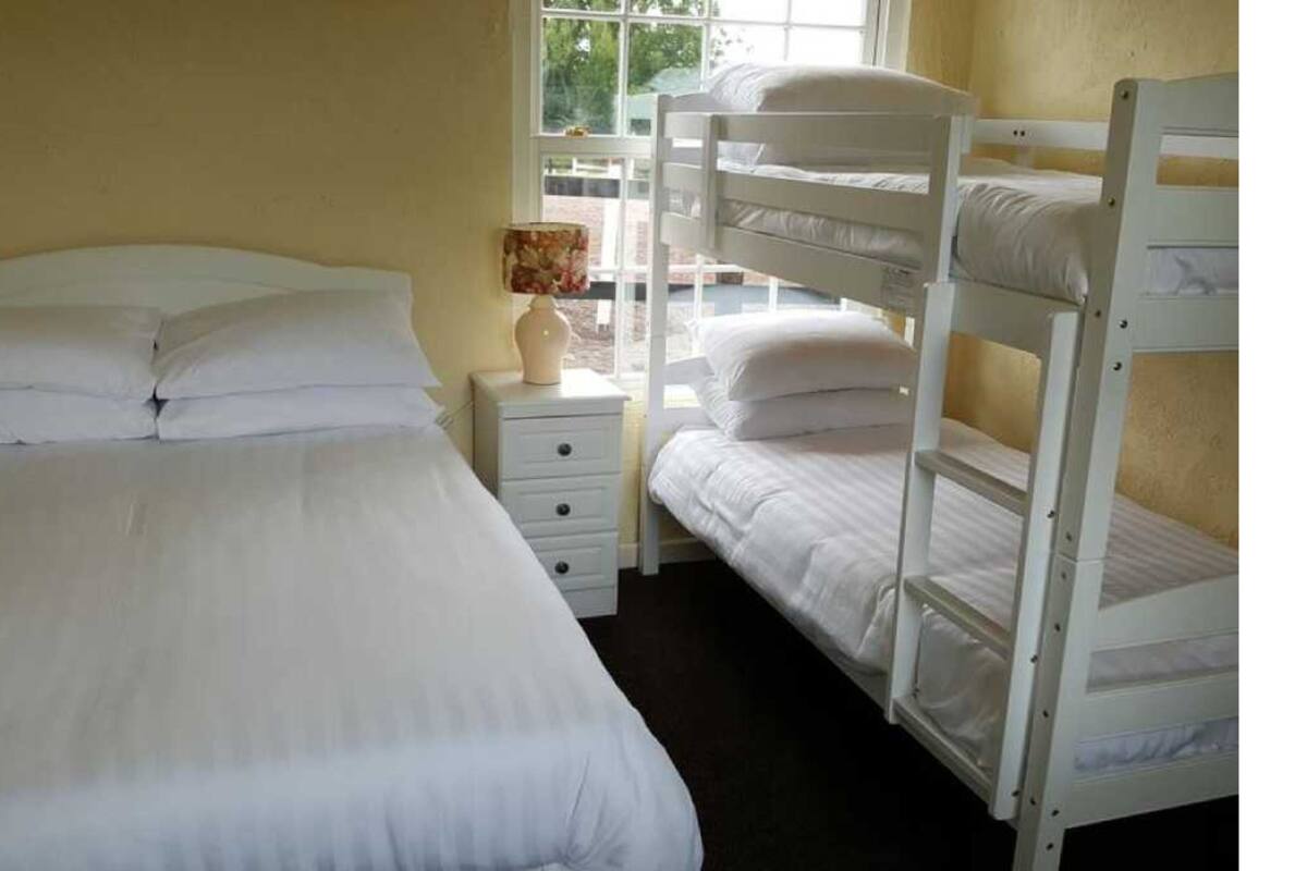 A room with a single bed, a nightstand, and a window.
