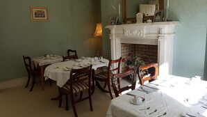 A dining room with a fireplace, multiple tables set for dining, and chairs. - Cannaway House B&B (Macroom)