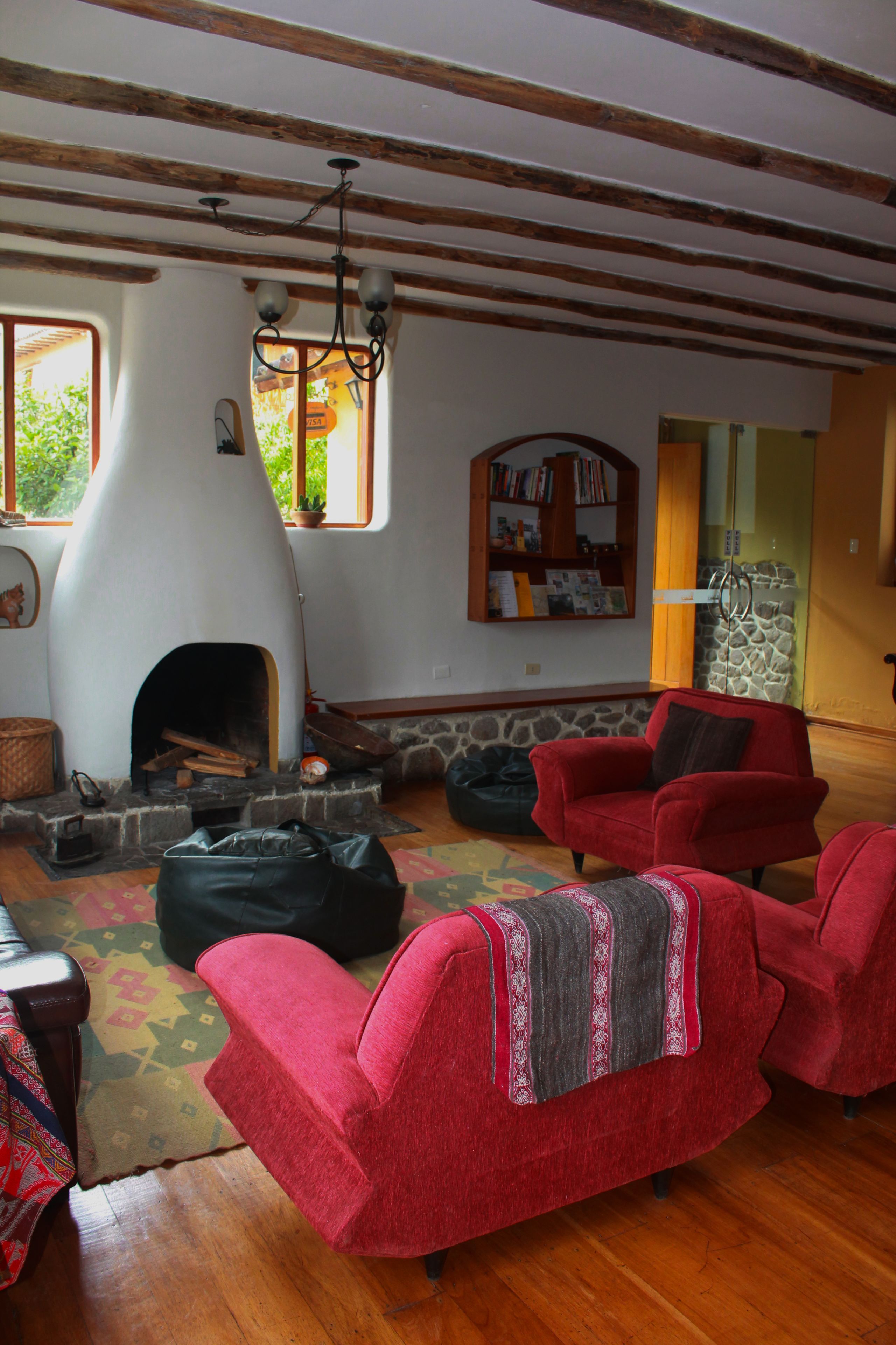 A cozy living room with a stone fireplace, red armchairs, and a bookshelf.