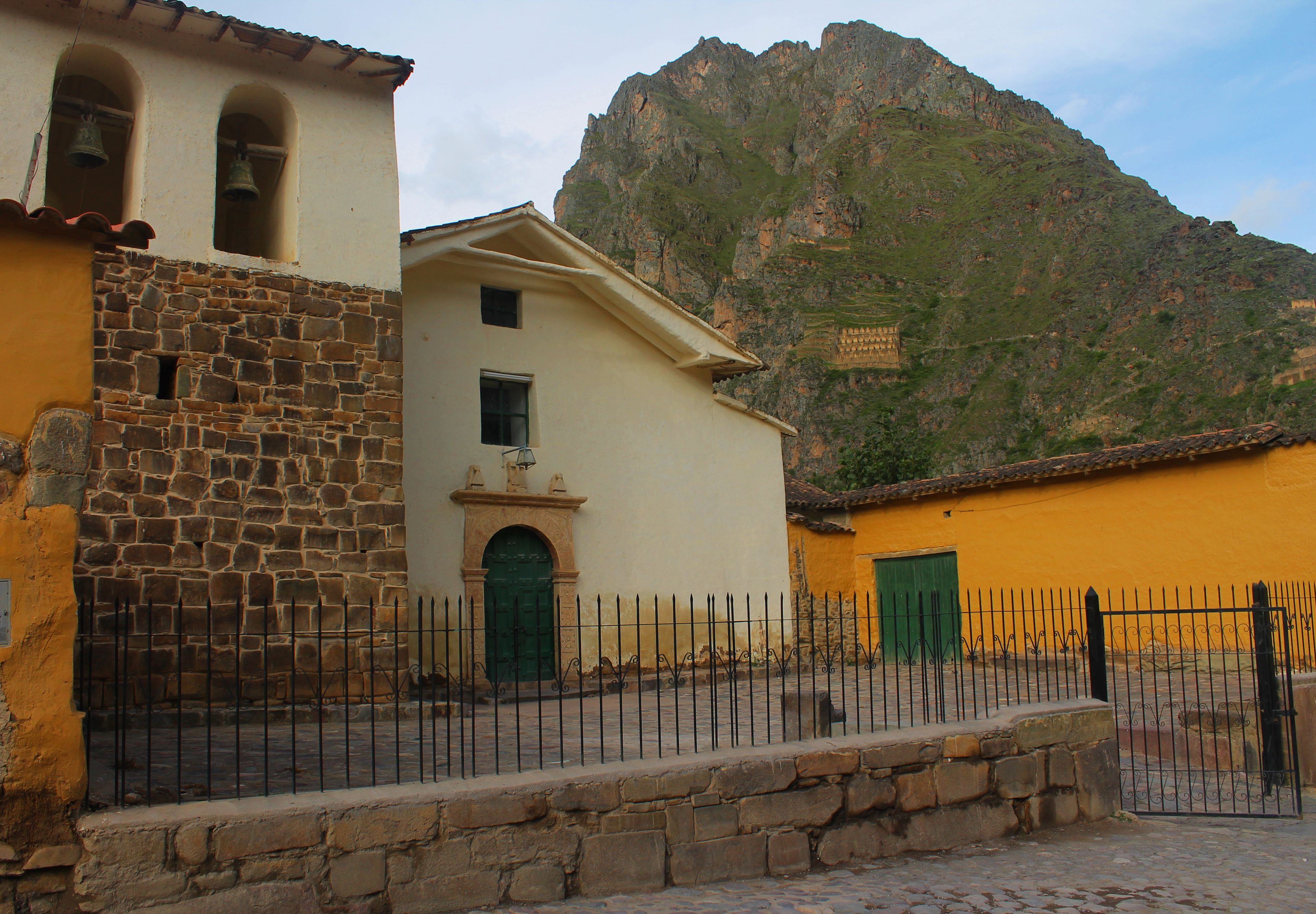 Un edificio con fachada de piedra y pared amarilla, una puerta verde y un campanario.
