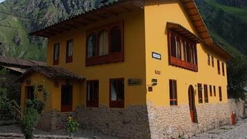 Un edificio amarillo con paredes de piedra y ventanas de madera, situado en una zona montañosa.