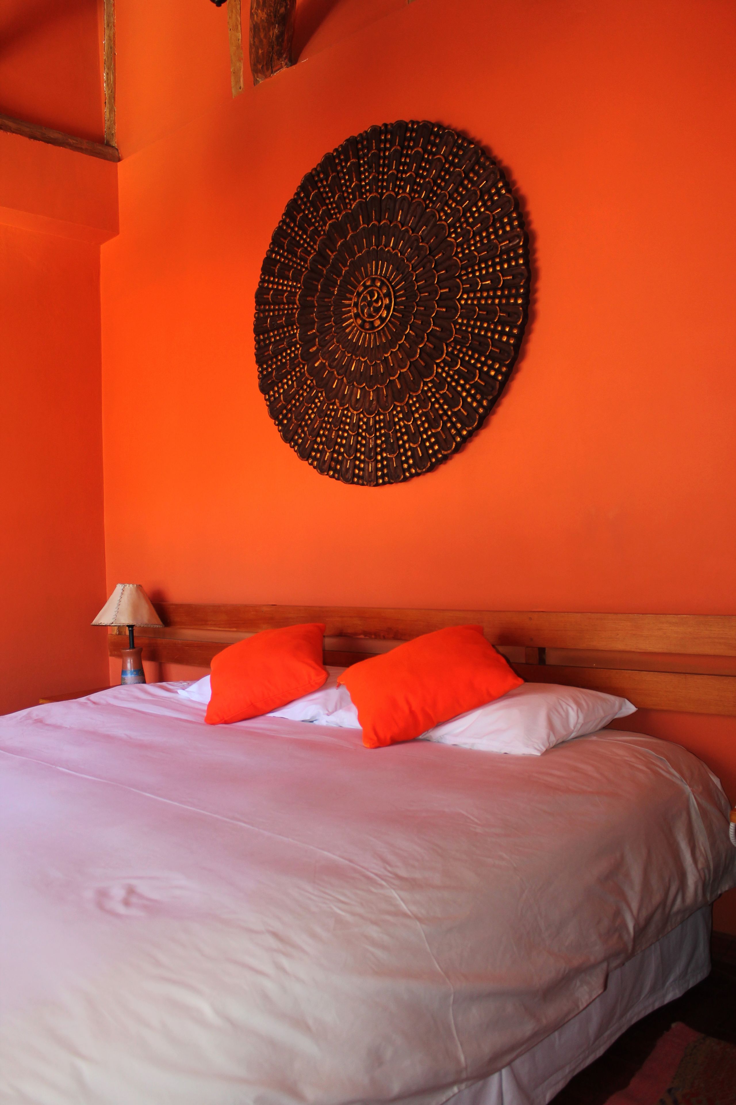 A room with a bed, orange walls, and a circular wall decoration.