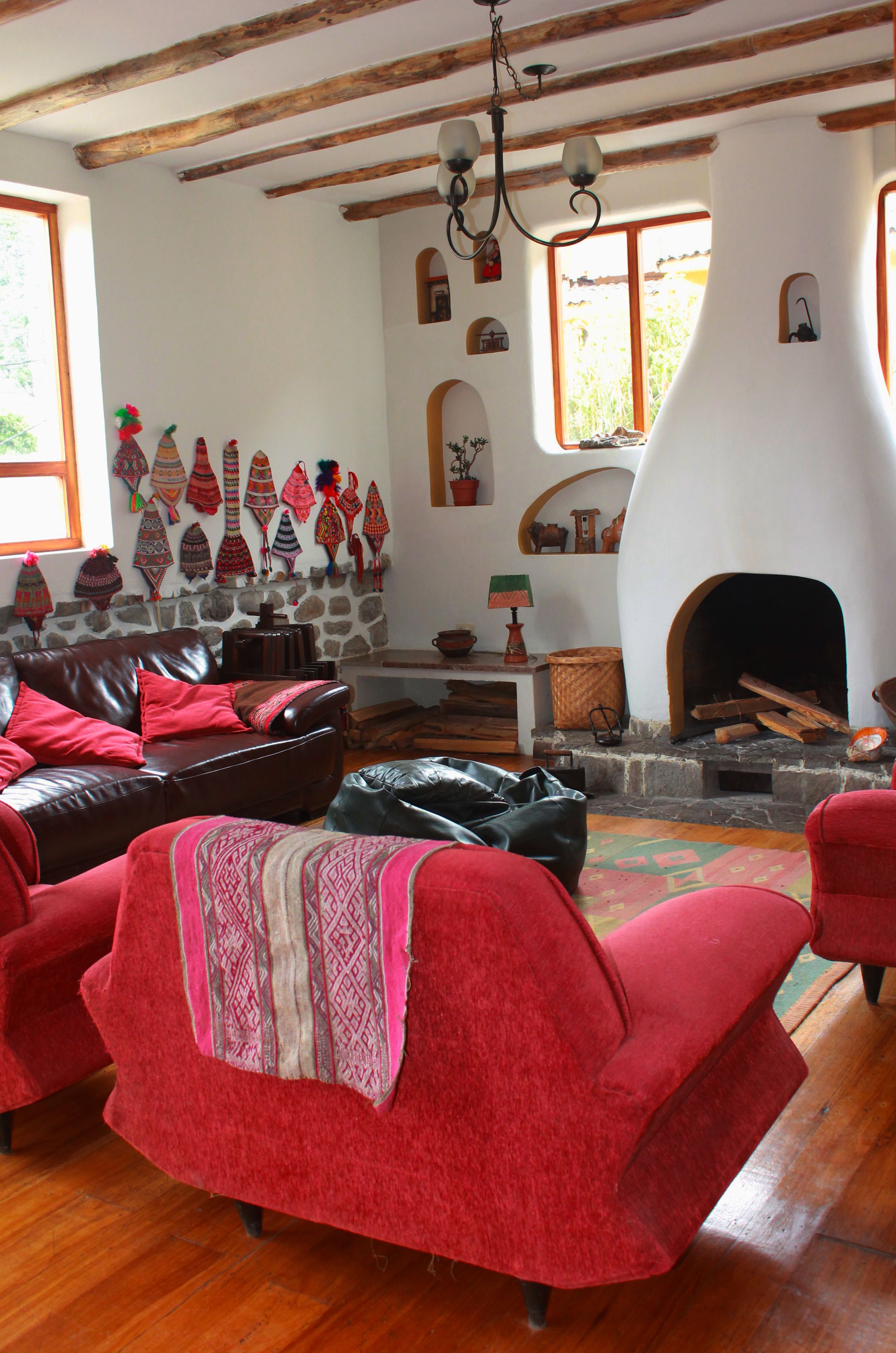 A cozy living room with a fireplace, red sofas, and a stone wall with decorative items.