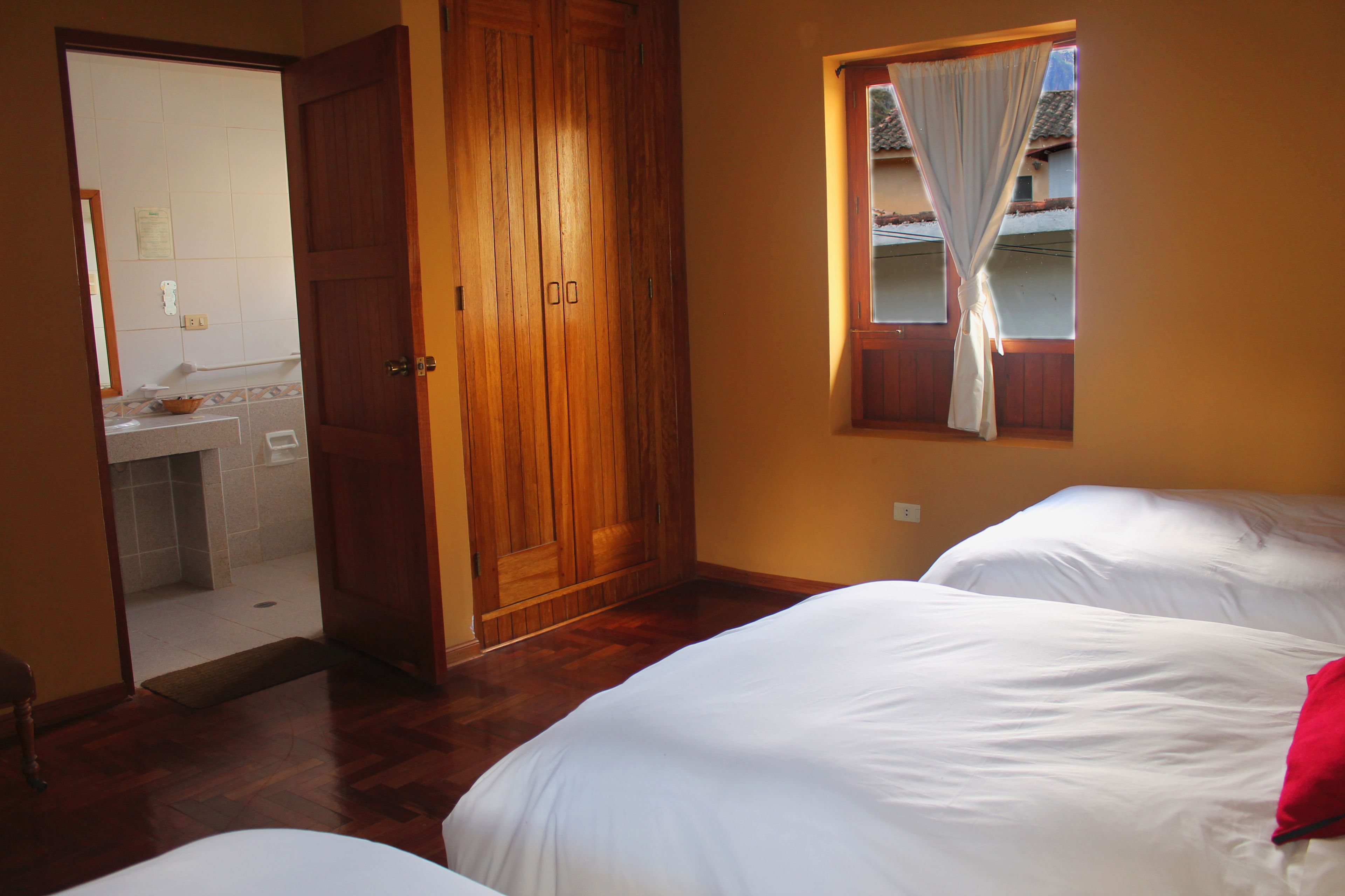 Un dormitorio con dos camas, un armario de madera y una ventana con cortinas.