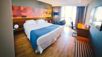 Ein modernes Hotelzimmer mit einem großen Bett, einem Schreibtisch und einem Sessel.