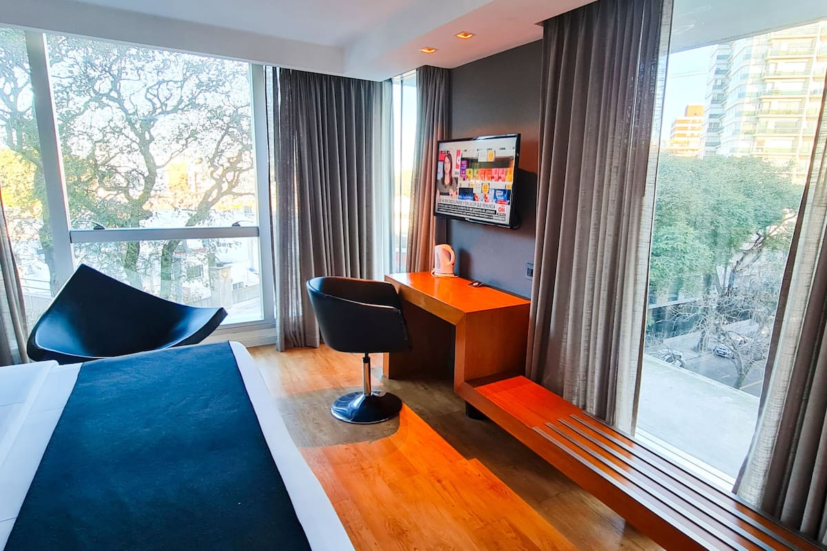 A hotel room with a bed, a desk, a chair, and a TV.