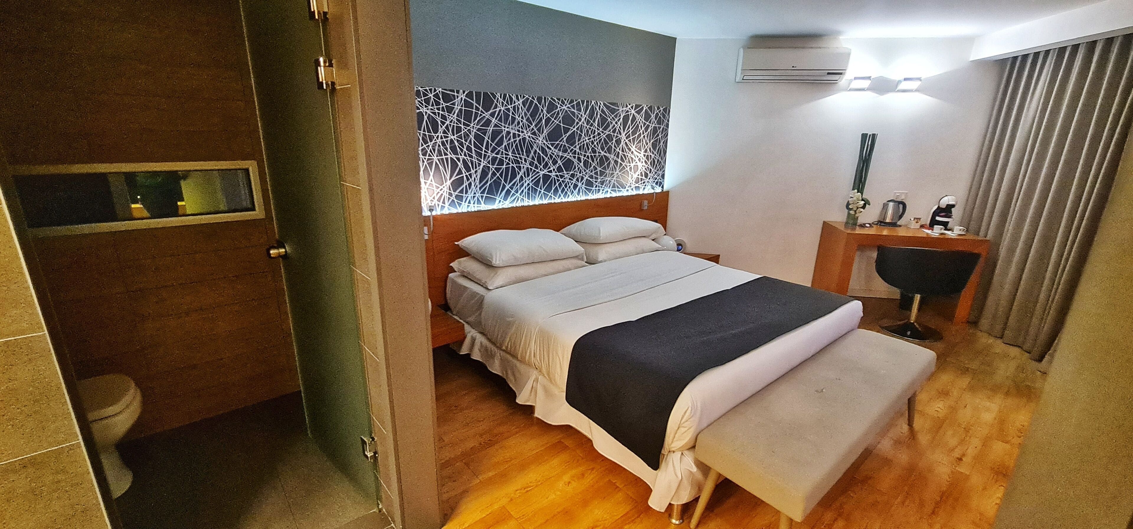 Une chambre d’hôtel avec un lit, une table de chevet et un petit bureau avec une chaise.
