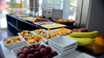 Un bufé con frutas y platos variados.