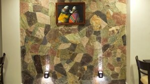 A wall with a mosaic pattern and a framed painting of two people. - Munay Ledesma (Libertador General San Martin)