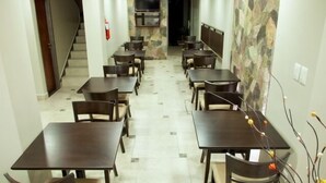 A dining area with multiple tables and chairs, a staircase, and a stone wall with a mounted TV. - Munay Ledesma (Libertador General San Martin)