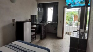 Habitación de hotel con cama, escritorio, kitchenette y televisor.