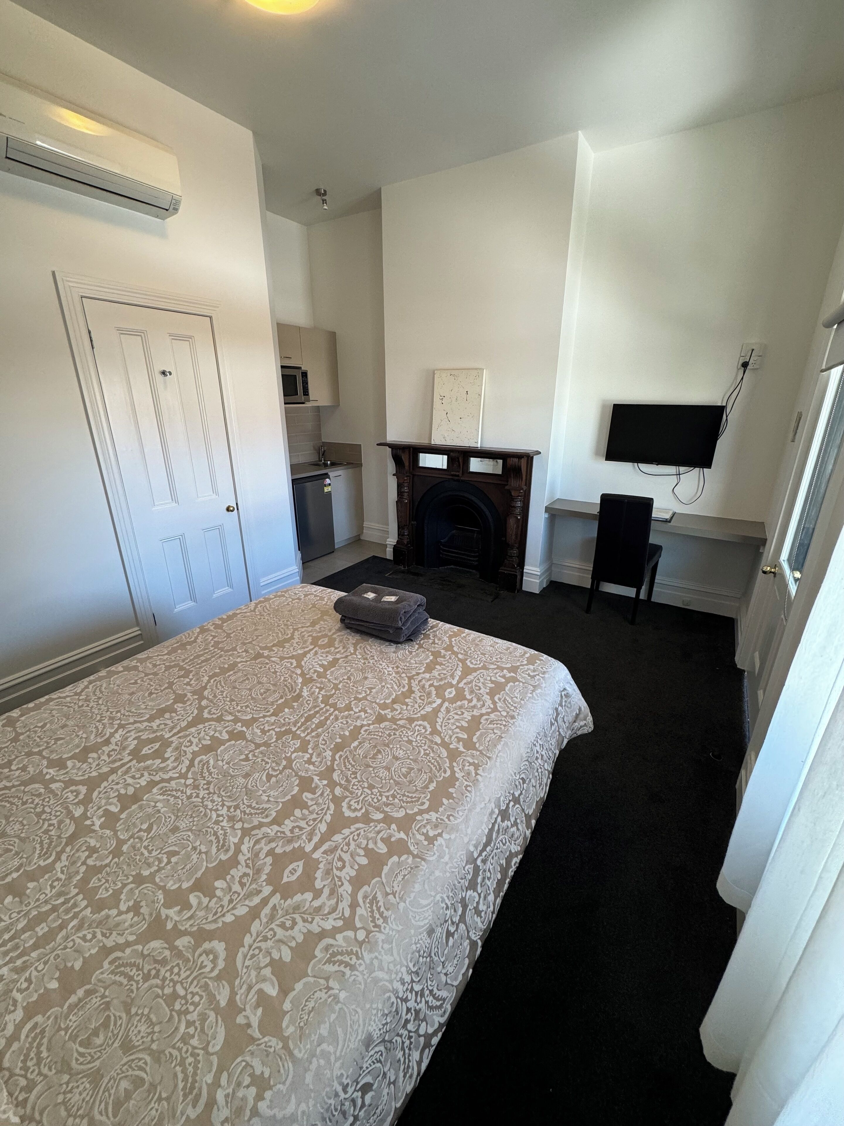 Una camera d'albergo con un letto, un camino, una TV e angolo cottura.
