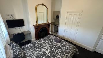Un dormitorio con cama, chimenea, televisión montada en la pared, armario y puerta.